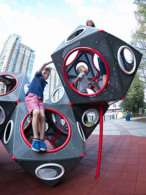 Children play on a cube shaped playground structures at a playground.